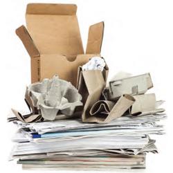 A stack of recyclable paper products including cardboard boxes and newspaper.